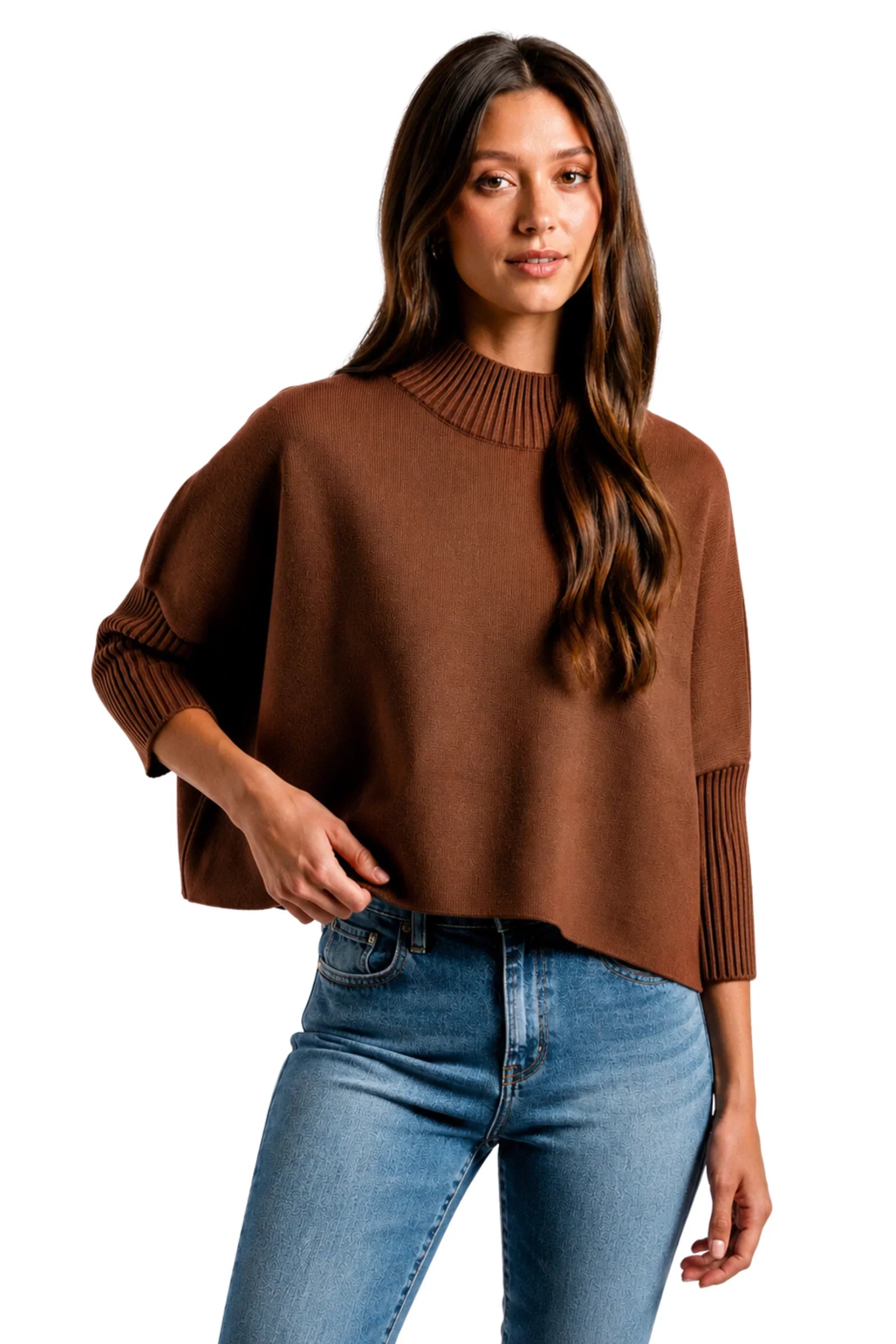 A woman wearing a brown knit mock-neck pullover sweater with ribbed three-quarter sleeves and blue jeans, photographed against a plain white background.